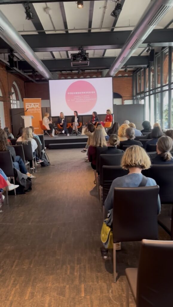 Leandra Fili moderiert eine Podiumsdiskussion beim DAK-Gesundheitsforum zu Prävention, Gesundheit und Wissenschaftskommunikation.
